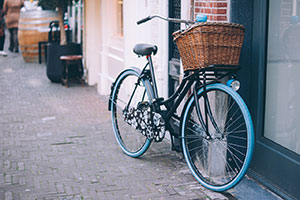 Blue Bicycle With Basket Leaning Against A Wall On The Road.