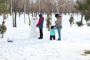 Family Of Three (parents And Kid) Building Snowman.
