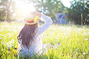 Woman Under Sun Light In Flower Field.