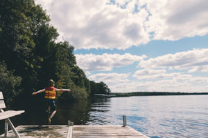 Kid Jumping Off A Dock Into A Lake.