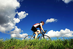 Man Riding Bike In The Summer On Grass Field.