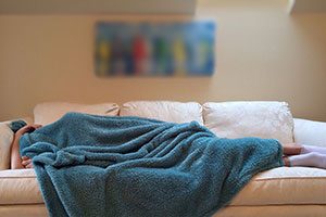Woman Sleeping Under Blanket On Couch.