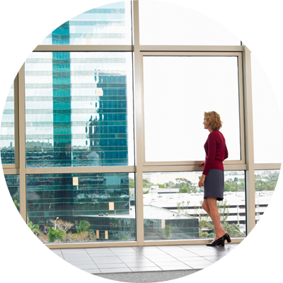 Business woman standing in office looking out the window.