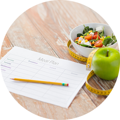 Meal plan chart, pencil, salad bowl, green apple and measurement tape on wooden table.