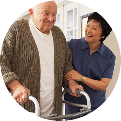 Personal support worker helping senior man walk with walker.
