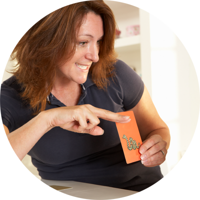 Speech Language Pathologist holding an orange card with drawing of a snake on it.