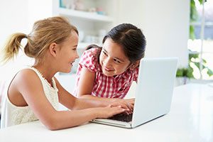 Two Young Girls Using A Laptop At Home.