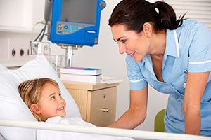 Female Pediatric Nurse At Bedside Of Young Female Patient.