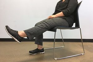 Female Doing Knee Extension Exercise While Sitting In A Chair.