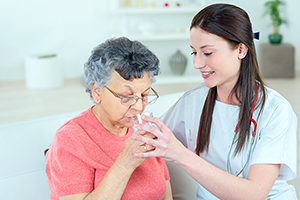 Personal Support Worker (PSW) Helping A Woman Drink.