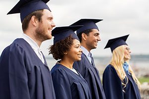 Four People Graduated From Social Work Programs, All Dressed In Graduation Robes, Smiling.