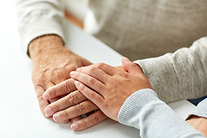 Close-up Of Home Care Providers Holding Seniors' Hands.