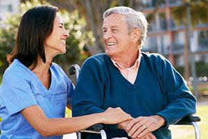 Personal Support Worker (PSW) Kneeling With Male Senior In Wheelchair.